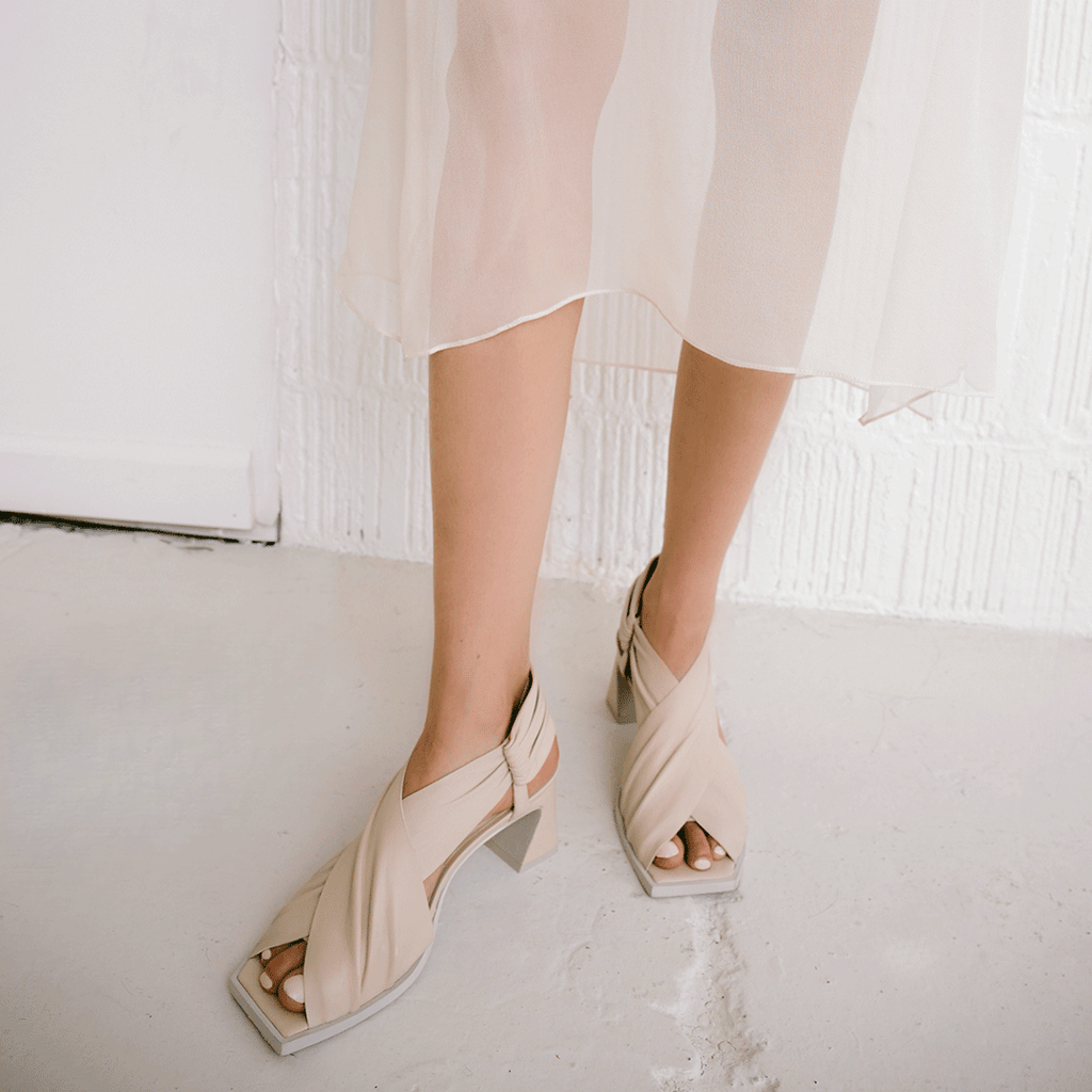 Daniella Shevel Harper in stone white wrap leather sandal with square toe with light skirt