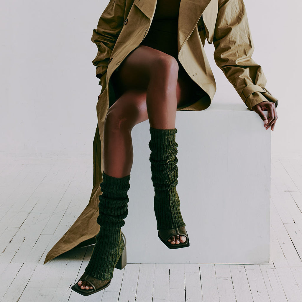 Daniella Shevel Onyx olive ankle boots paired with a textured sock and trench coat for bold styling.