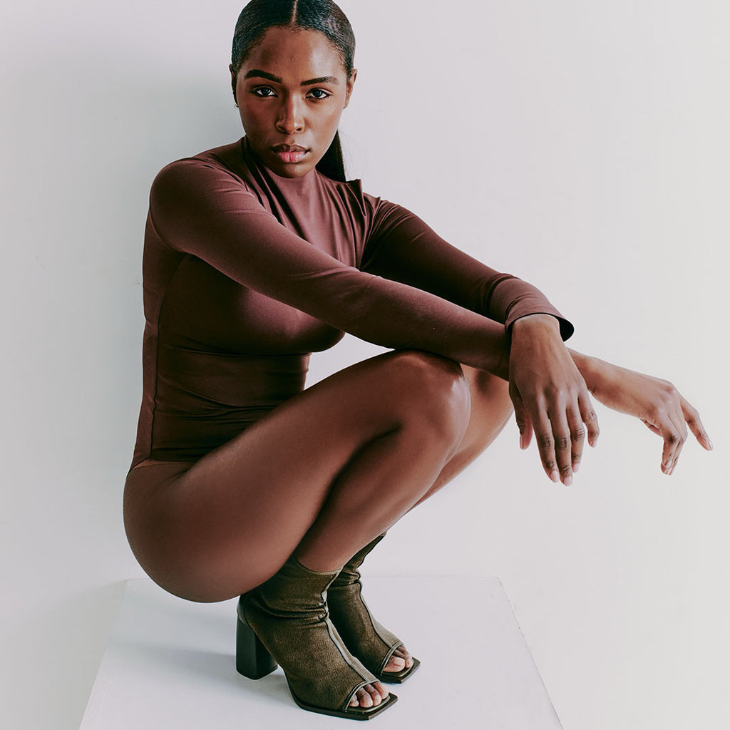 Daniella Shevel Onyx olive ankle boots paired with a minimal bodysuit, styled for understated elegance.