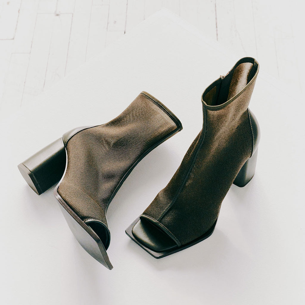 Front view of Daniella Shevel Onyx olive ankle boots, emphasizing their sleek square-toe silhouette and structured heel.