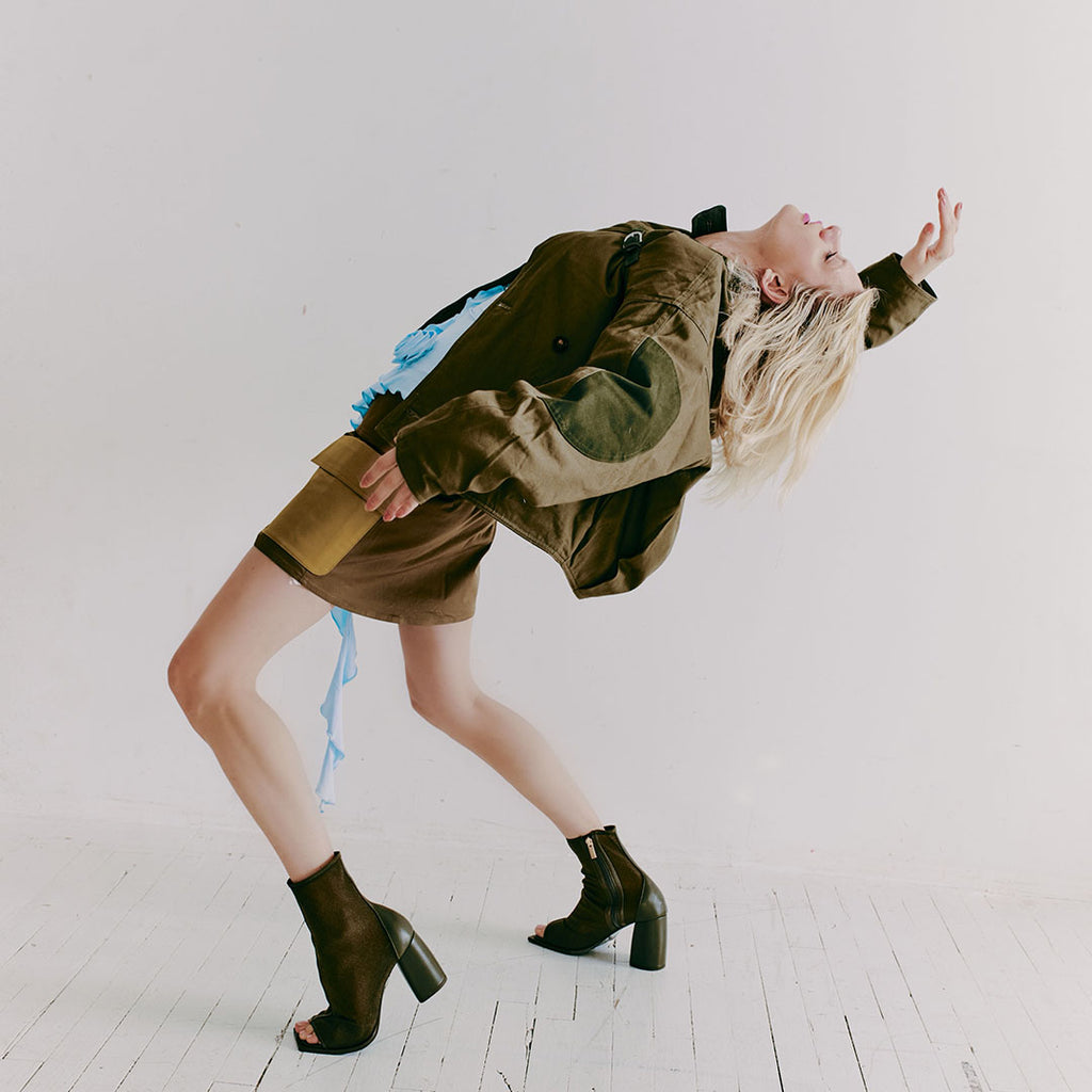 Model wearing Daniella Shevel Onyx olive ankle boots with a bold outfit, highlighting their versatility in movement.