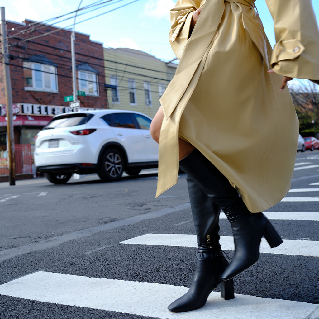 Daniella Shevel Tall to the knee black boot in stretch leather with buttercup yellow coat at cross street intersection